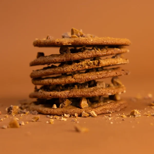 Golden-brown Toffee Almond cookies stacked on a wooden board